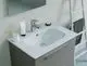Waschtisch mit glattem Waschbecken und moderne Armatur von Ideal Standard. Auf dem Tisch befinden sich Zahnbürsten, eine Tube und ein Handtuch im Hintergrund.